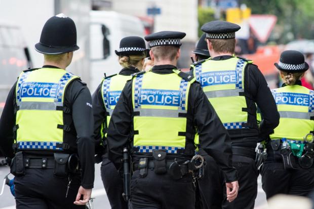 Six British Transport Police officers patrol the street in Highbury, London
